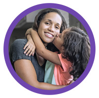 Young daughter kissing smiling mother on the cheek.